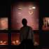 A person, who can only be seen as a shadow, looks at jewellery and objects in a display case at the State Archaeological Collection in Munich.