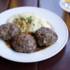 A plate of meatballs and mashed potatoes stands next to a beer
