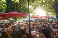The beer garden at Viktualienmarkt filled with guests on a sunny day in Munich.