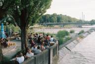 Several people are sitting on the banks of the Isar at the Kulturstrand in Munich, enjoying the good weather.
